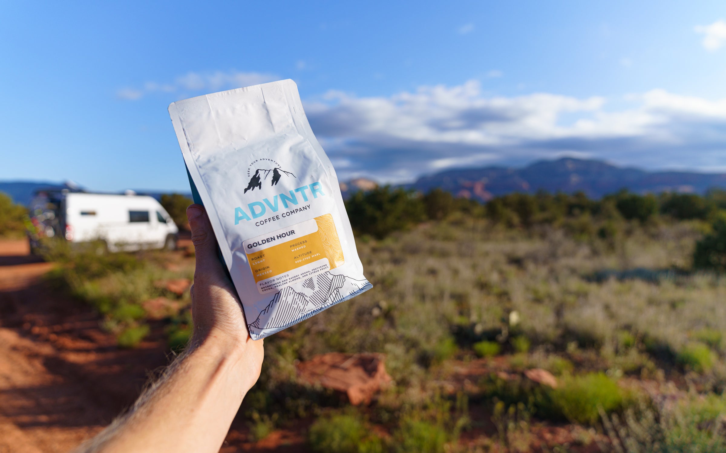 Hand holding bag of ADVNTR Coffee with campervan and mountain in the background in Sedona Arizona